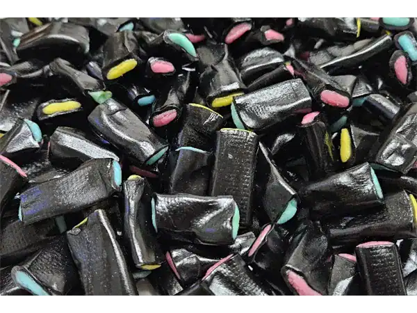 Close-up of colorful black licorice candies with pastel accents, highlighting delicious chewy sweets from Roch Sweets.