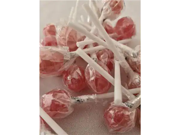 Colorful hard candies with white sticks arranged on a surface.