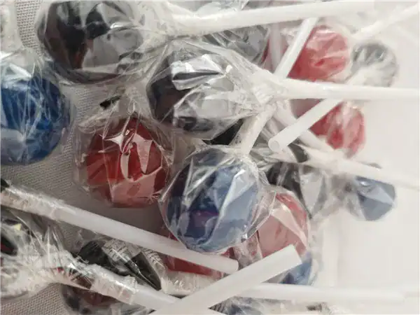 Colorful lollipops wrapped in clear plastic on sticks, appealing and delicious treats.